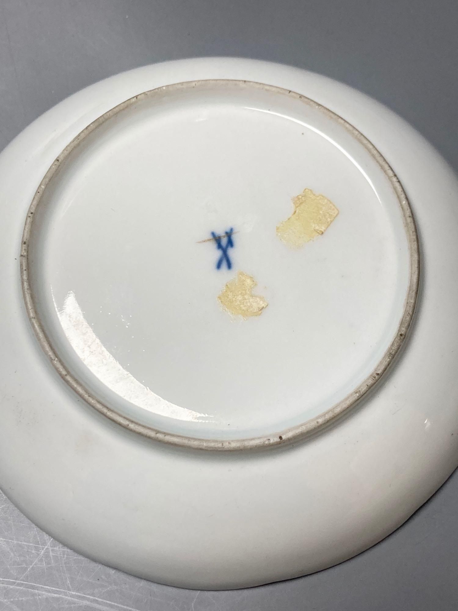 A Meissen cup and saucer, factory seconds, decorated with fruit and butterflies and lined with gilt